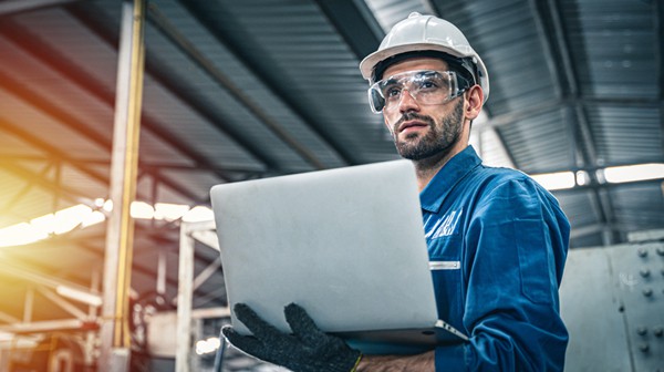 Factory worker focused while holding laptop at a factory